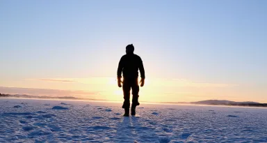 En person som står i motljus på ett snöigt fält