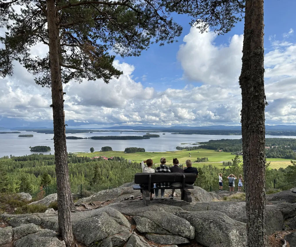 Fyra personer som sitter på en bänk uppe på Avholmsberget med utsikt över Dellen