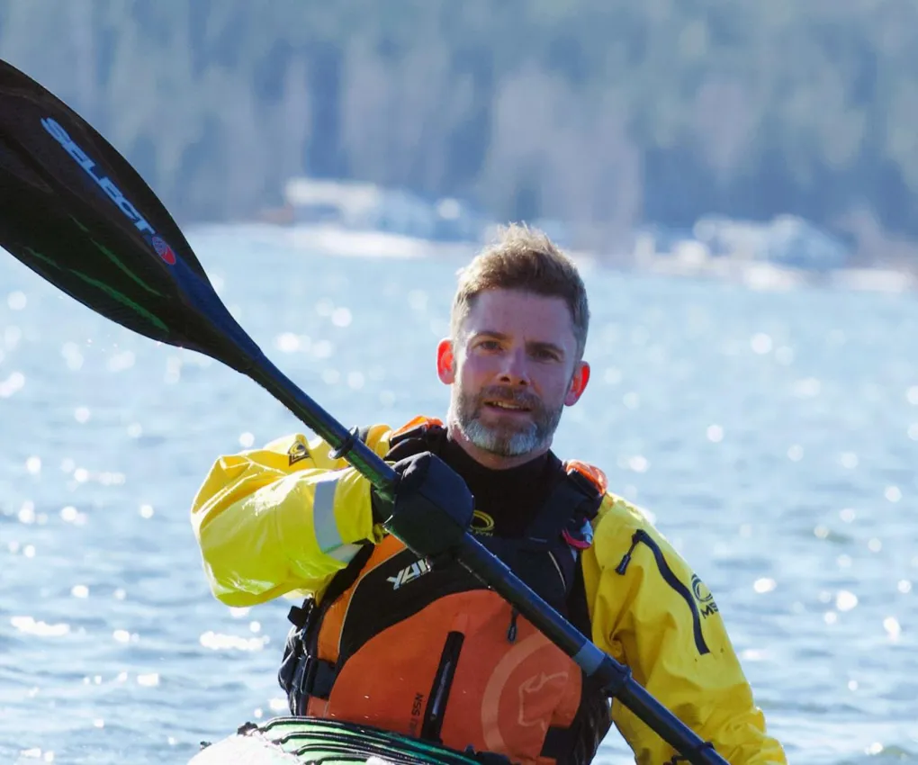 En man som paddlar kajak på glittrigt vatten