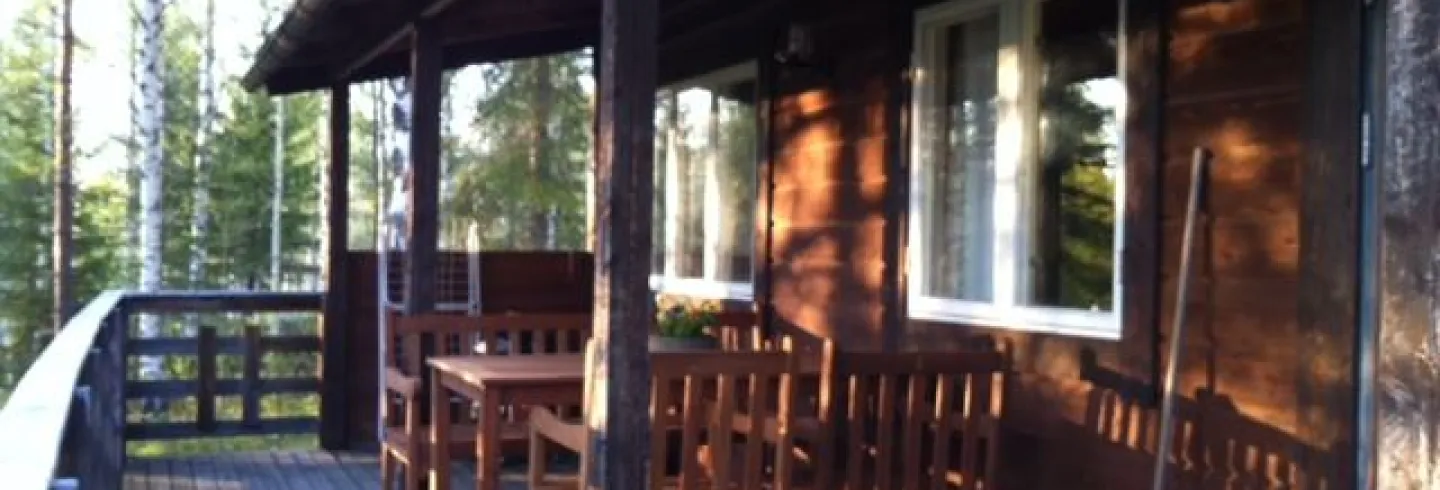Veranda med utsikt mot sjön och sittgrupp under tak. Grill.