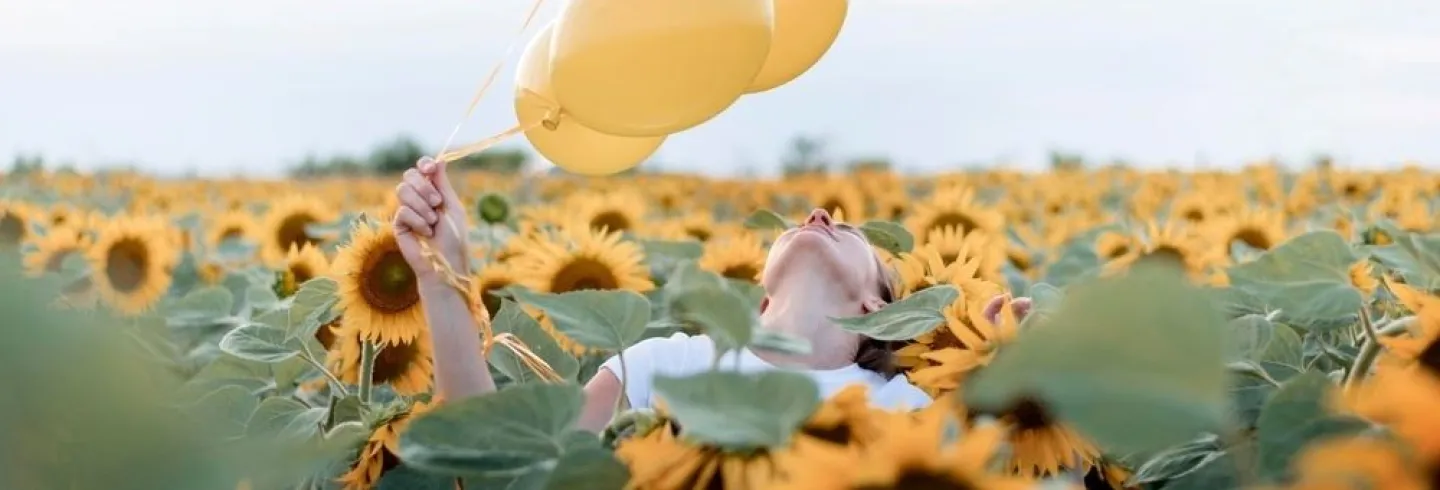 	53037400-woman-holding-balloons-sunflower-field.jpg