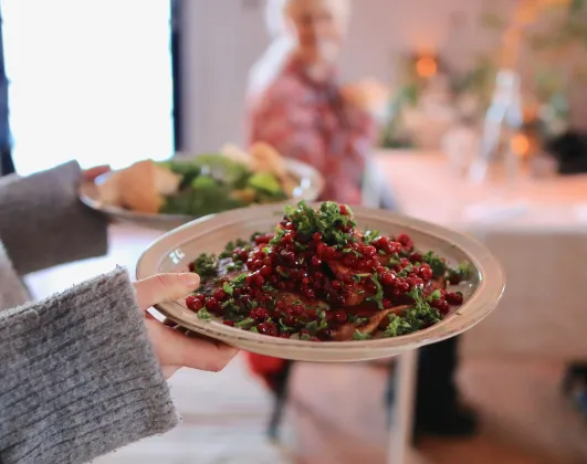 en person serverar rårakor med lingon och persilja