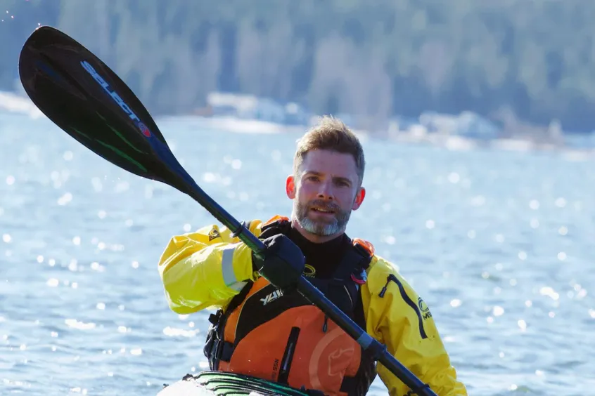 En man som paddlar kajak på glittrigt vatten