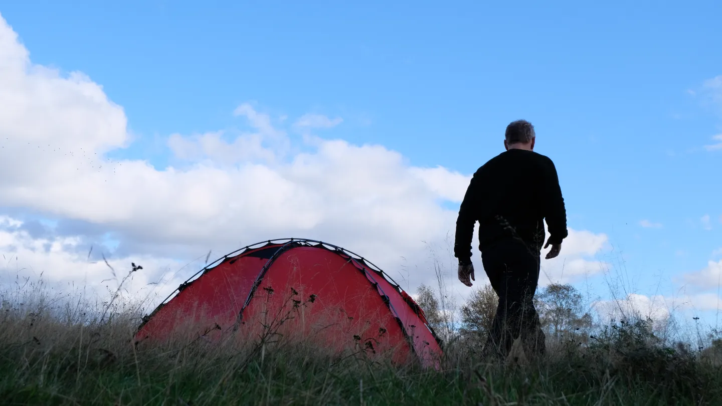 En människa bredvid ett rött tält