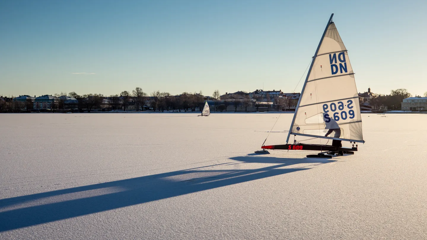 En isjakt står uppstäld på en snötäkt is en solig dag